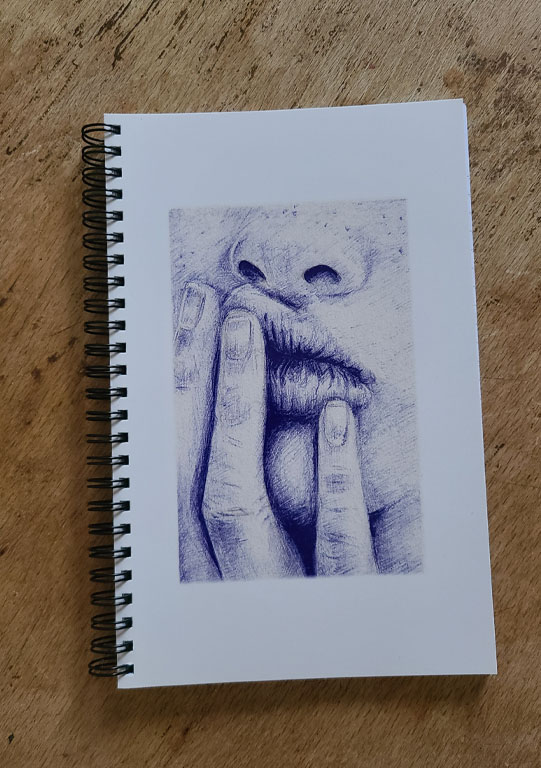 carnet à spirales illustré par un dessin au stylo bic d'une bouche boudeuse